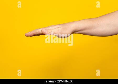 Forte braccio dell'uomo con palmo disteso capovolto isolato su sfondo giallo. Foto Stock