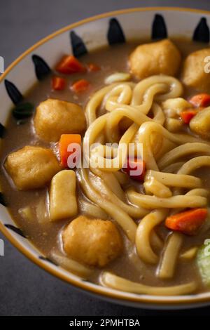 Una ciotola di tagliatelle calde al palato cucinate in una fragrante salsa al curry Foto Stock