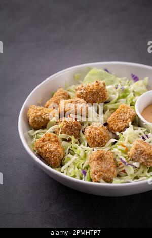 Un recipiente bianco riempito con una varietà di cibi colorati, tra cui una salsa da immersione e un'insalata di contorno Foto Stock