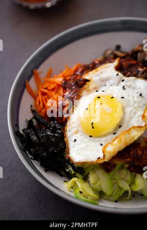 Immagine di una ciotola di porcellana bianca con un uovo singolo posto sopra un mucchio di alimenti assortiti Foto Stock