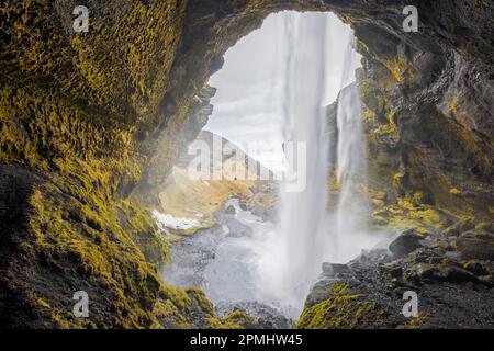 Cascata di Kvernufoss sul fiume Kverna, vista dall'interno di una piccola grotta dietro le cascate d'acqua in inverno, Skógar, Rangárþing eystra, Islanda del Sud Foto Stock