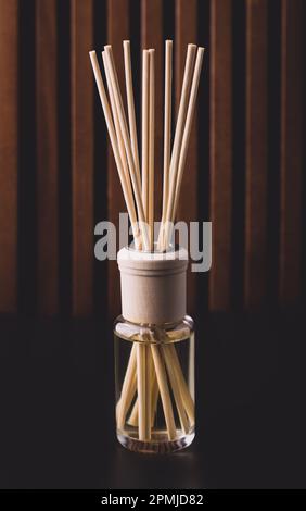 bottiglia di fragranza per la casa con bastoncini di rattan e odore di freschezza su fondo scuro Foto Stock