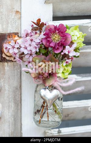 Bouquet di rose di lenten e ciliegia fiorita giapponese in bottiglia di vetro Foto Stock