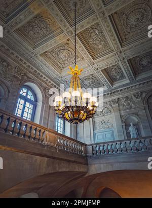 Dettagli architettonici di una sala scala decorata con un lampadario d'epoca appeso al soffitto del Palazzo di Versailles, Francia Foto Stock