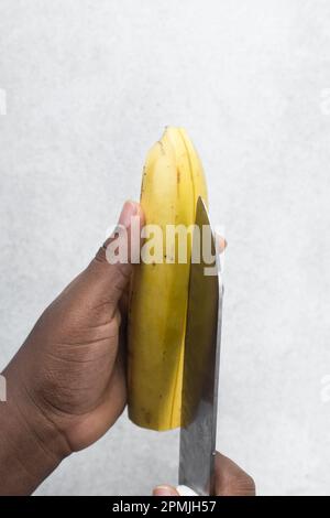 Mani che sbucciano le plantane mature, le plantane gialle per friggere che vengono sbucciate, procedimento per preparare la plantana fritta Foto Stock