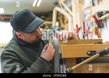 Utensili in lavorazione del legno. Artigiano focalizzato utilizzando la staffa e marcatura su legno con una matita. Interno dell'officina carpentiere. Foto di alta qualità Foto Stock