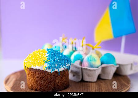 Torta di Pasqua decorata in colori di bandiera Ucraina e uova dipinte in giallo blu, disposti intorno ad essa. concetto di pasqua, tradizioni ucraine. Supporto U Foto Stock