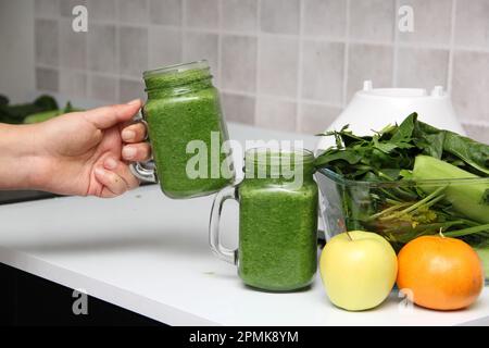 Succo verde servito in un barattolo di mason con verdure come cetriolo, bietola, spinaci, limone e frutta per una colazione sana e nutriente Foto Stock