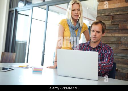 La collaborazione è fondamentale. due designer che lavorano su un notebook in ufficio. Foto Stock