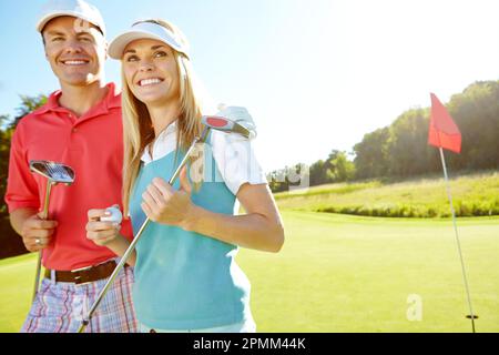 Tezzatura off. Coppia giovane attraente con i loro randelli di golf e palle sul verde. Foto Stock