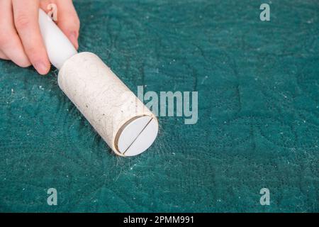 Mano dell'uomo con un rullo adesivo per pulire i tessuti - maglione in  maglia di lana da polvere, capelli, pelucchi e lanugine, vista dall'alto,  primo piano Foto stock - Alamy