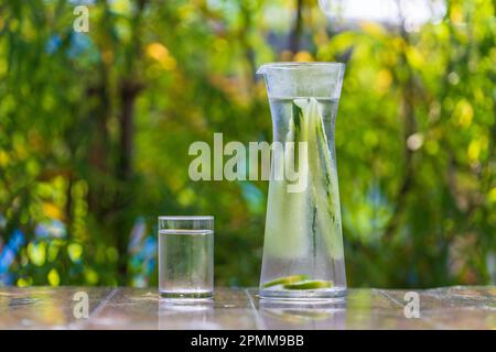Acqua in vetro con cetriolo e limone su tavola di legno in un caffè tropicale, Thailandia, da vicino Foto Stock