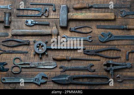 Strumenti vintage visualizzati su uno sfondo di legno, primo piano, vista dall'alto. Set di attrezzi di lavoro vecchi sporco Foto Stock