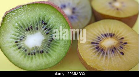 Kiwi tagliati su un tagliere giallo. Il giallo è chiamato Actinidia chinensis o kiwifruit dorato. Il verde si chiama Actinidia deliciosa Foto Stock