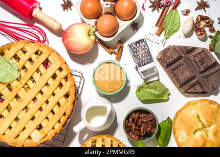 Torta d'autunno e torte di cottura sfondo. Mele dolci, pecan, torte di zucca con ingredienti da forno e utensili, tavola bianca vista dall'alto Foto Stock