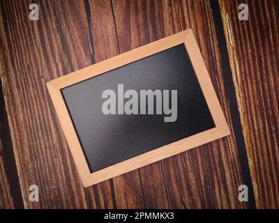 Vista dall'alto una semplice lavagna nera su uno sfondo di legno. Foto Stock