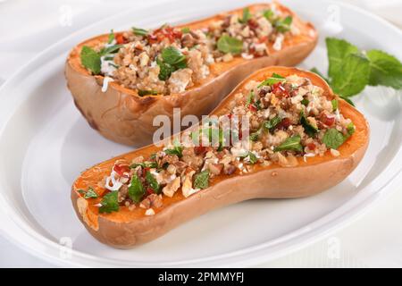 Zucca farcita al forno ripiena di noci, menta fresca e peperoncino con tovbouleh di quinoa. Lo sciroppo d'acero li rende eccellenti. È un contorno sano Foto Stock