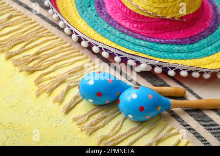 Maracas messicane con cappello sombrero e serape su sfondo giallo, primo piano Foto Stock