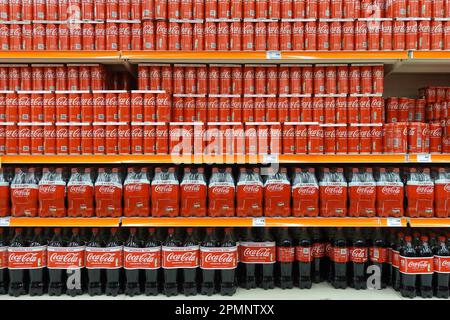 Atene, Grecia - 6 marzo 2023: Scaffali impilati con lattine e bottiglie per bibite analcoliche Coca Cola di varie dimensioni. Foto Stock