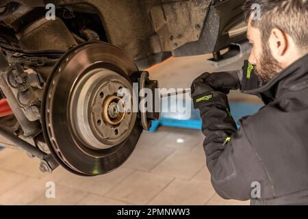 Milano, Italia 11 aprile 2023: Meccanico esperto sostituisce con precisione e cura le pastiglie dei freni di una vettura. Foto Stock