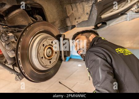 Milano, Italia 11 aprile 2023: Meccanico esperto sostituisce con precisione e cura le pastiglie dei freni di una vettura. Foto Stock
