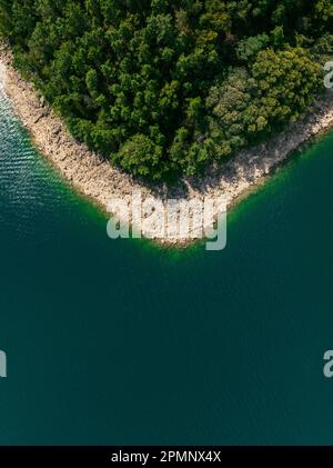 Questa splendida fotografia aerea cattura le acque azzurre di un lago tranquillo, circondato da una lussureggiante vegetazione verde Foto Stock