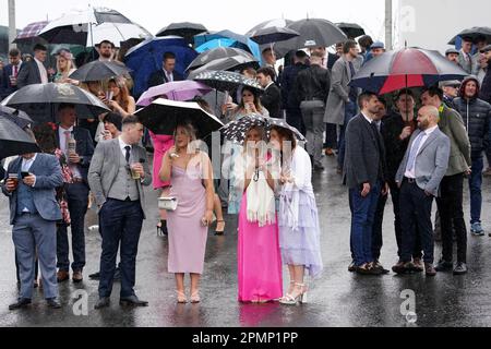 I Racegoers attendono la terza gara in condizioni di bagnato durante il secondo giorno del Randox Grand National Festival all'Aintree Racecourse di Liverpool. Data immagine: Venerdì 14 aprile 2023. Foto Stock