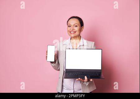 Una donna d'affari in gravidanza mostra smartphone e notebook con schermo digitale bianco e mockup per annunci pubblicitari o app mobili Foto Stock