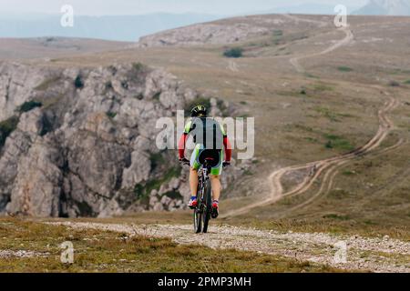 gli alpinisti maschili corrono in bicicletta su un sentiero montano in una gara di sci di fondo Foto Stock