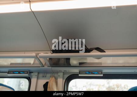 Zaino turistico nero su uno scaffale di un treno. Concetto di viaggio. Bagagli su scaffale di un autobus. Foto Stock