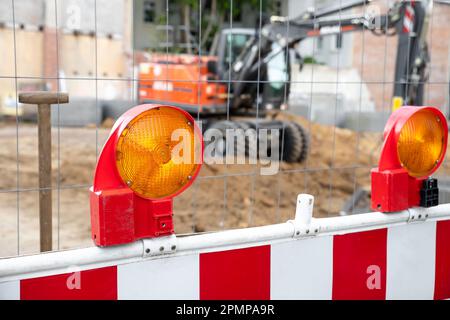 Primo piano vista dettagliata lampeggiatore arancione barriera fotoelettrica di sicurezza contro recinzione area di lavoro cantiere. Attrezzatura di sicurezza lampada fusibile barricata Foto Stock