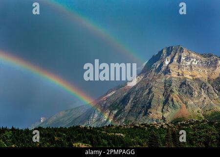 Doppio arcobaleno con montagna e cielo blu scuro nel Waterton Lakes National Park; Waterton, Alberta, Canada Foto Stock