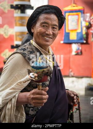 Uomo tibetano in abiti tradizionali con una ruota di preghiera; Lhasa, Tibet Foto Stock