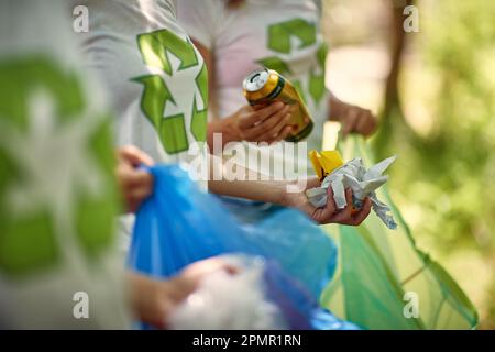 Vista ravvicinata dei rifiuti raccolti da giovani volontari nella foresta in una bella giornata estiva. Ecologia, persone, cura Foto Stock