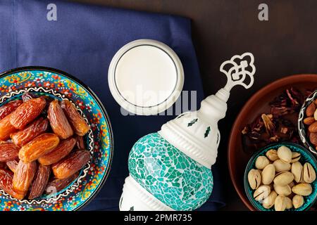 Ramadan Kareem cibo e bevande. Frutta da datare, noci e latte su sfondo scuro. Ramadan kareem il concetto del mese di digiuno. Vista dall'alto Foto Stock