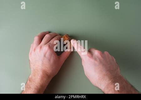 La mano di un uomo tiene i tappi tagliati e li taglia. Preservazione dell'ecologia del pianeta. Materie prime per il riutilizzo. Protezione ambientale. Foto Stock