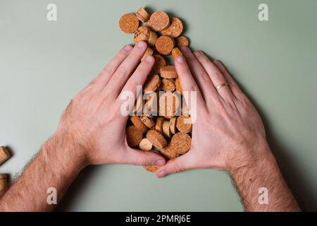 La mano di un uomo tiene i tappi tagliati e li taglia. Preservazione dell'ecologia del pianeta. Materie prime per il riutilizzo. Protezione ambientale. Foto Stock