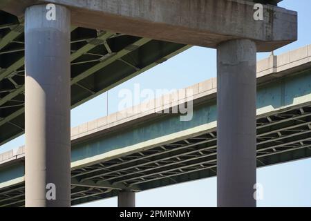 Vista astratta della sopraelevata autostrada interstatale dal basso. Pilastri in calcestruzzo con struttura a trave in acciaio verde Foto Stock