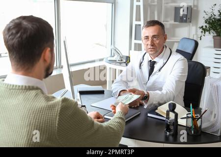 Paziente che dà la tangente al medico in clinica Foto Stock