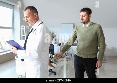 Paziente che dà la tangente al medico in clinica Foto Stock