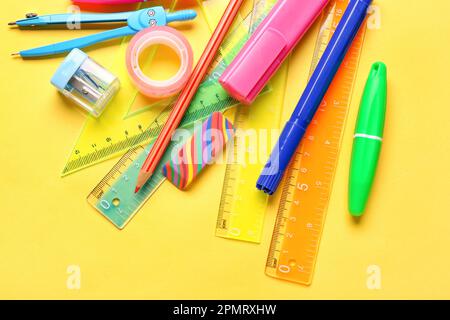 Articoli di cancelleria colorati su sfondo giallo Foto Stock