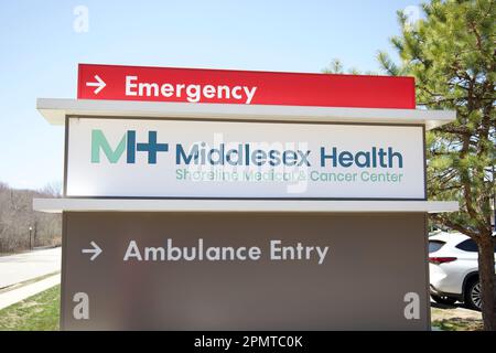 Segno che dice: Emergenza | Middlesex Salute Shoreline Medical & Cancer Center | Ambulance entrata. Alberi, strada, e cielo sullo sfondo. Foto Stock