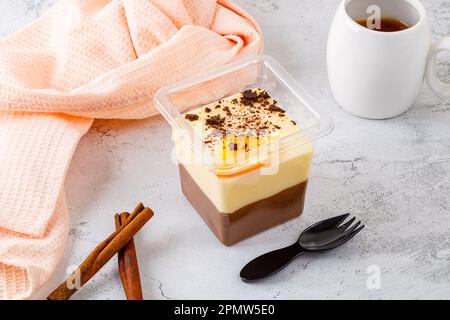 Dessert tiramisù in una scatola di plastica con forchetta su fondo di cemento. Foto di alta qualità Foto Stock