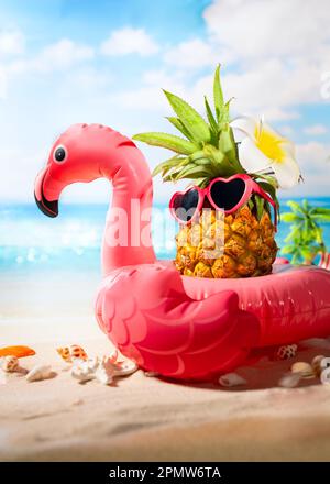 Fenicottero rosa gonfiabile e ananas hipster in occhiali da sole. Estate piscina galleggiante party idea. Concetto creativo estivo. Foto Stock