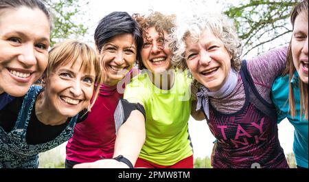 Felice multi generazionale donne che si divertono insieme al parco cittadino - multigenerazionale donne amici che prendono selfie dopo l'allenamento sportivo all'aperto - luminoso Foto Stock