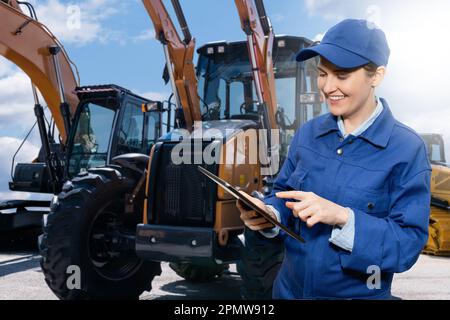 Donna con tablet digitale sullo sfondo di macchine da costruzione. Foto di alta qualità Foto Stock