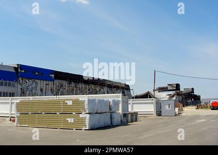 Un cantiere edile dopo un incendio di magazzino, strutture bruciate. Stoccaggio di pannelli sandwich in pile in cantiere. L'edificio bruciato a causa di t Foto Stock