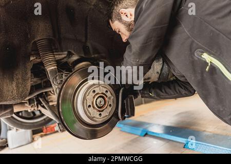 Un meccanico esperto sostituisce le pastiglie dei freni di una vettura con precisione e cura. Foto Stock
