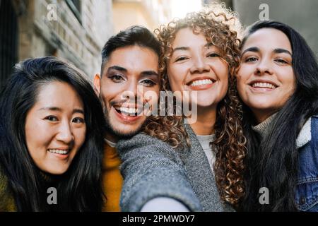 Diversi gruppi di amici che si divertono a prendere selfie all'aperto - Focus su gay transgender uomo vestire - concetto di vacanze di viaggio Foto Stock