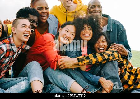 Gruppo vario di persone che si divertono all'aperto - giovani amici multirazziali che festeggiano insieme - Focus sul volto asiatico della donna Foto Stock